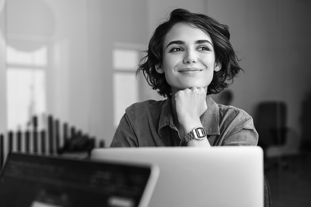 Hymyilevä nainen tietokoneen ääressä.