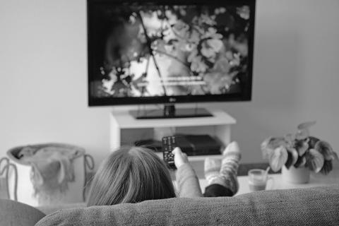 nainen katsoo tv-ohjelmaa, jossa on tekstitys