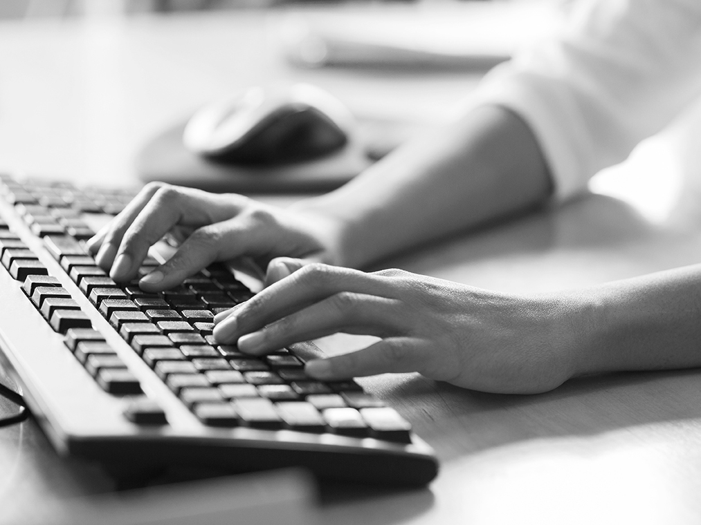 Hands on keyboard, on a desk.